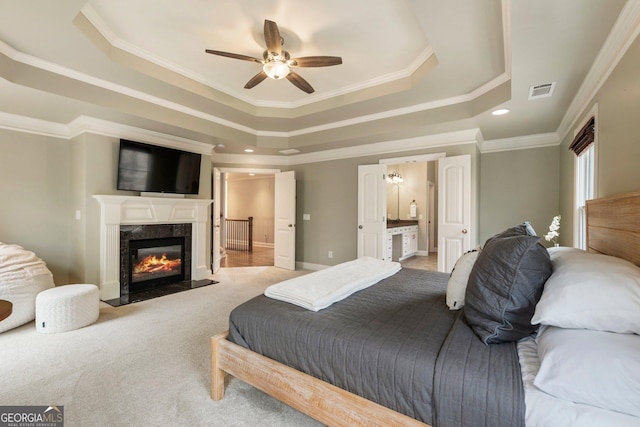 bedroom with visible vents, a tray ceiling, carpet floors, ornamental molding, and a fireplace