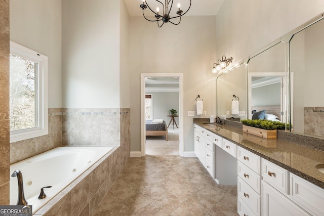 ensuite bathroom featuring double vanity, connected bathroom, a tub with jets, and a sink