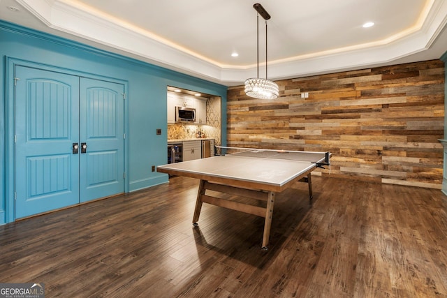 rec room with ornamental molding, a tray ceiling, recessed lighting, wine cooler, and dark wood-style flooring