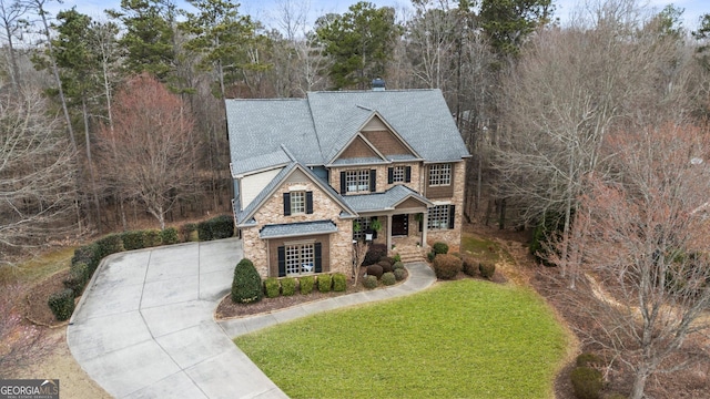 view of front of property with stone siding, driveway, and a front lawn