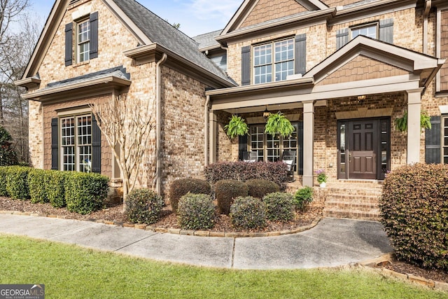 view of exterior entry featuring brick siding and covered porch