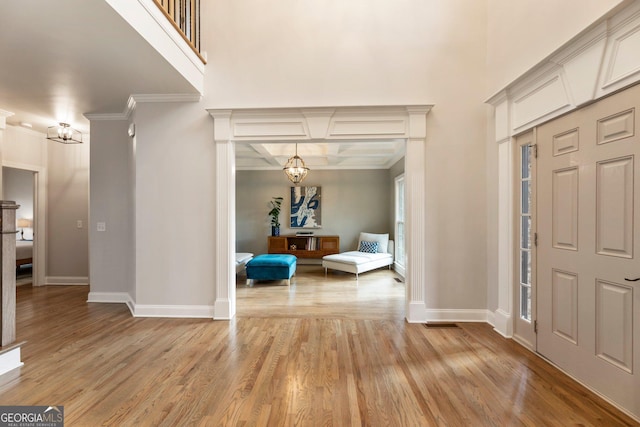 foyer with baseboards, light wood-style floors, a high ceiling, and ornamental molding