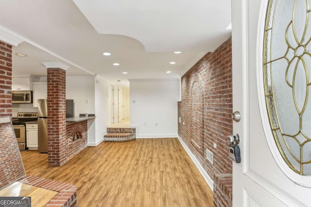 entryway with visible vents, baseboards, brick wall, light wood-style flooring, and recessed lighting