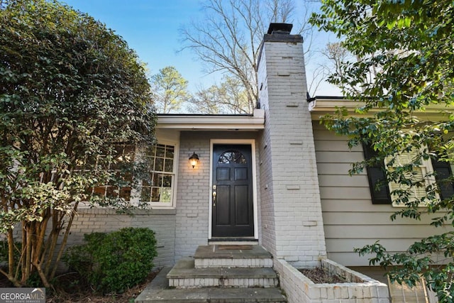 entrance to property with brick siding and a chimney