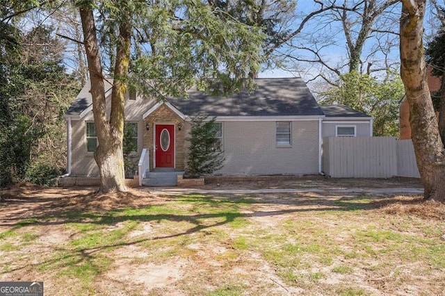 view of front of house featuring entry steps, brick siding, and fence