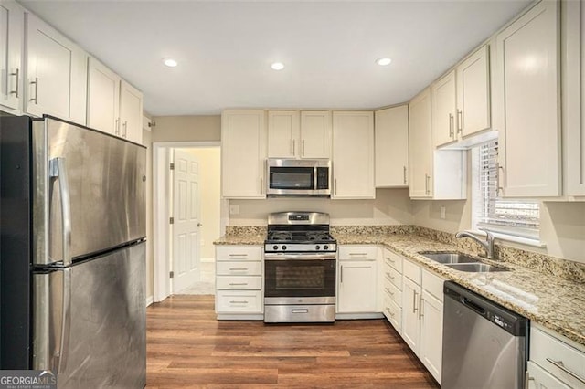 kitchen featuring light stone counters, dark wood finished floors, stainless steel appliances, recessed lighting, and a sink