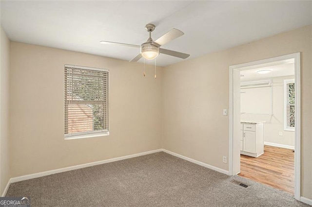 spare room featuring baseboards, visible vents, a ceiling fan, and light colored carpet