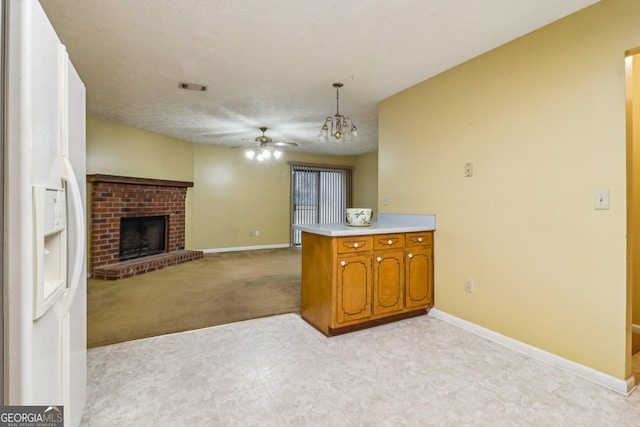 kitchen featuring white refrigerator with ice dispenser, a fireplace, light countertops, visible vents, and brown cabinetry