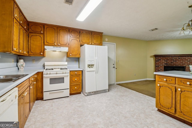 kitchen featuring white appliances, under cabinet range hood, brown cabinets, and light countertops