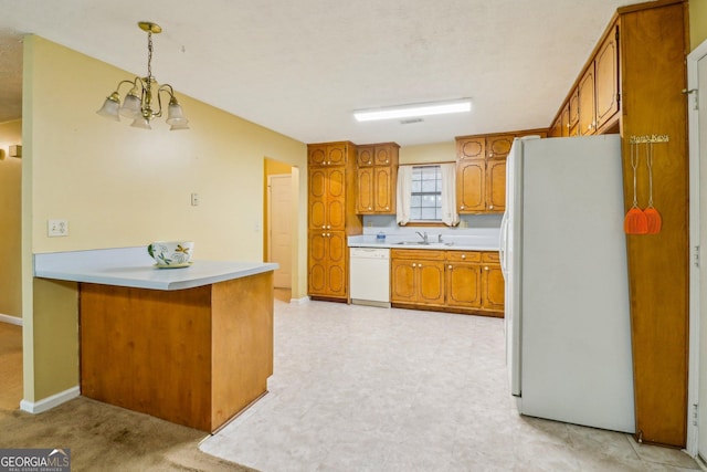 kitchen featuring a peninsula, white appliances, brown cabinets, and light countertops