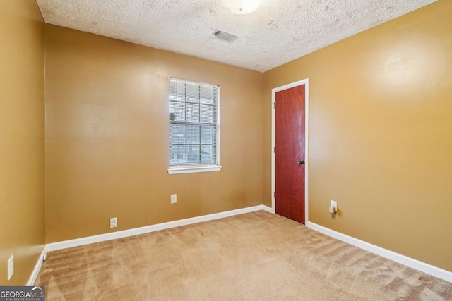 unfurnished room featuring carpet floors, baseboards, visible vents, and a textured ceiling