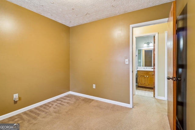 empty room featuring baseboards, a textured ceiling, and light colored carpet