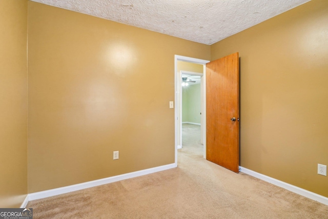 carpeted spare room featuring a textured ceiling and baseboards