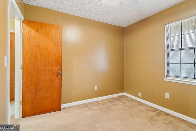 carpeted spare room with a textured ceiling and baseboards