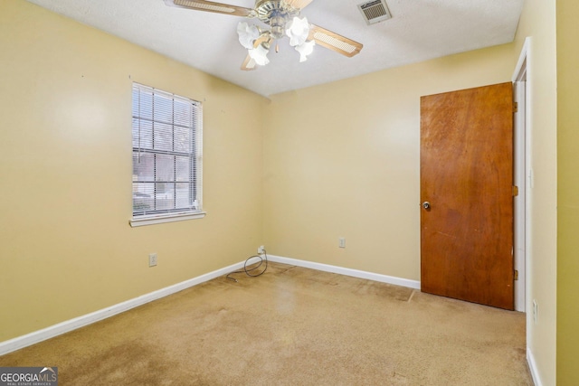 carpeted spare room with visible vents, ceiling fan, and baseboards