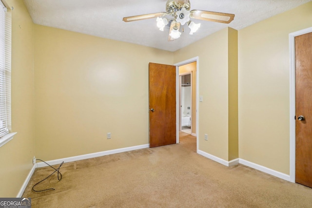 unfurnished room with carpet floors, a textured ceiling, baseboards, and a ceiling fan