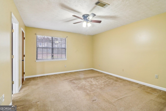 carpeted empty room with visible vents, ceiling fan, a textured ceiling, and baseboards