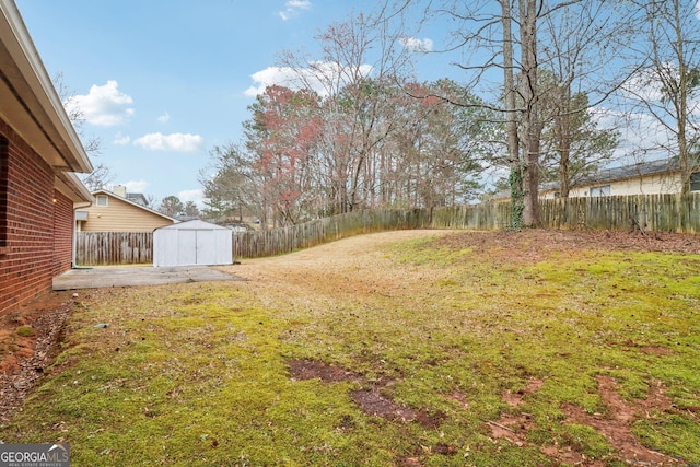 view of yard with an outbuilding, a patio area, a fenced backyard, and a shed