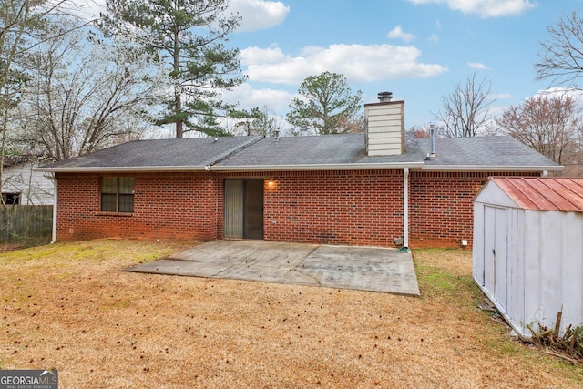 rear view of property featuring a lawn, a storage unit, an outdoor structure, a patio area, and brick siding