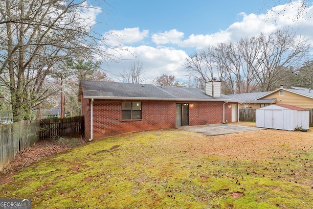 rear view of house with a patio area, brick siding, a fenced backyard, and a storage shed