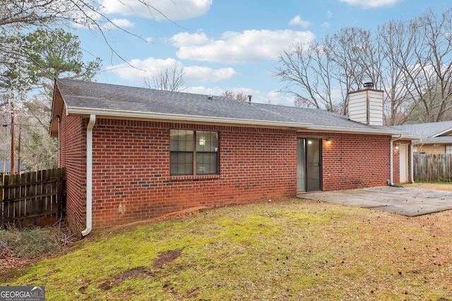 rear view of property featuring a patio area, fence, a chimney, and brick siding