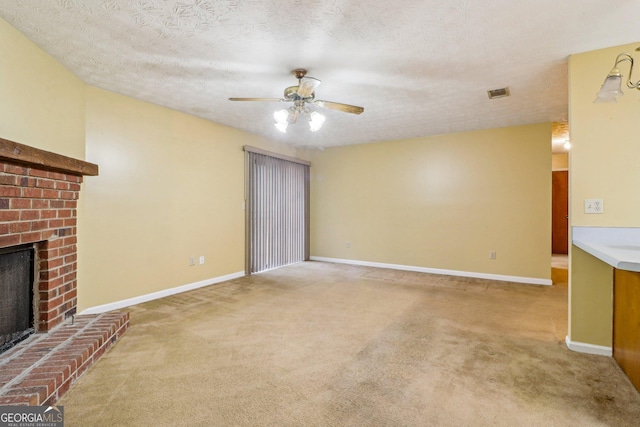 unfurnished living room featuring a textured ceiling, carpet flooring, visible vents, baseboards, and a brick fireplace