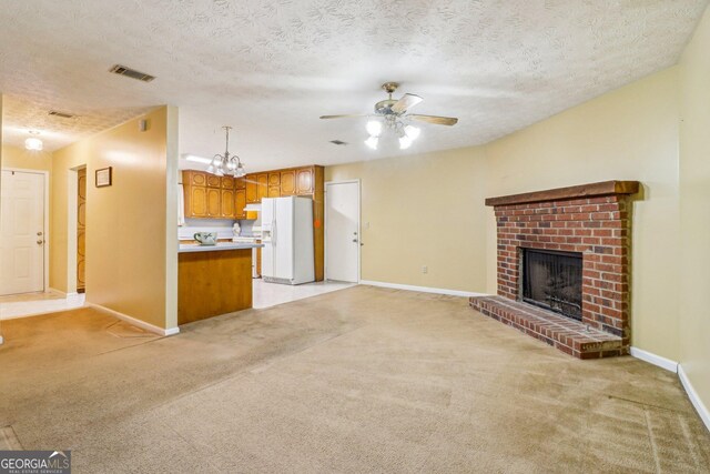 unfurnished living room with a fireplace, visible vents, a ceiling fan, and light colored carpet