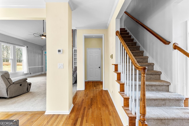 staircase with ceiling fan, crown molding, baseboards, and wood finished floors