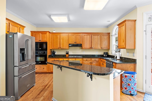 kitchen featuring a center island, ornamental molding, a sink, black appliances, and exhaust hood