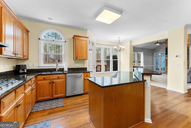 kitchen featuring stainless steel appliances, a sink, ornamental molding, light wood-type flooring, and a kitchen bar