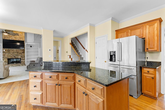 kitchen featuring light wood-style flooring, open floor plan, crown molding, a fireplace, and high end fridge