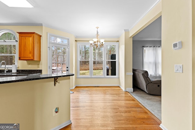 dining area featuring baseboards, light wood-style flooring, a chandelier, and crown molding