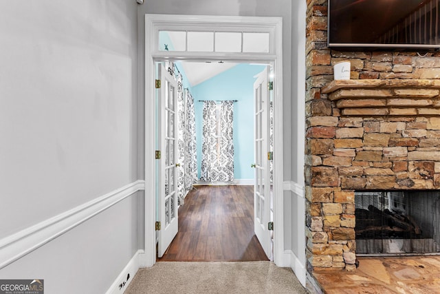 corridor with baseboards, vaulted ceiling, and carpet flooring