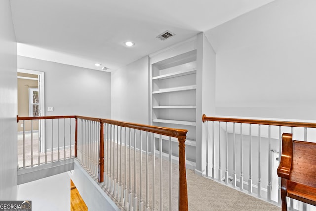 hall with visible vents, an upstairs landing, carpet floors, built in shelves, and recessed lighting