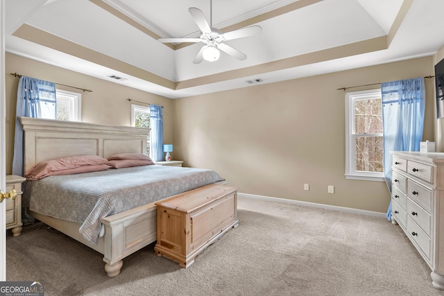 bedroom with light colored carpet, a ceiling fan, baseboards, visible vents, and a tray ceiling