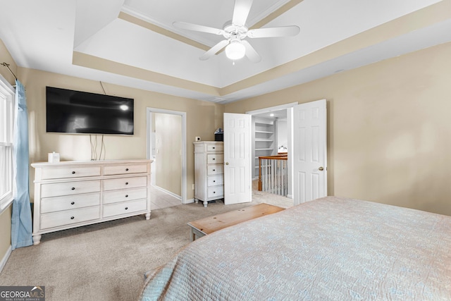 bedroom with baseboards, carpet, a tray ceiling, and a ceiling fan