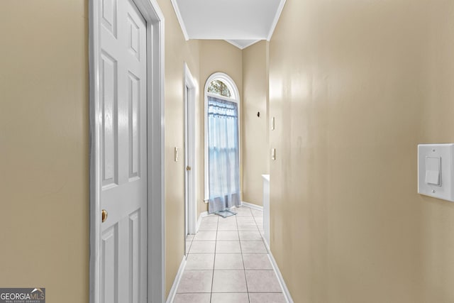 hallway featuring crown molding, baseboards, and light tile patterned floors