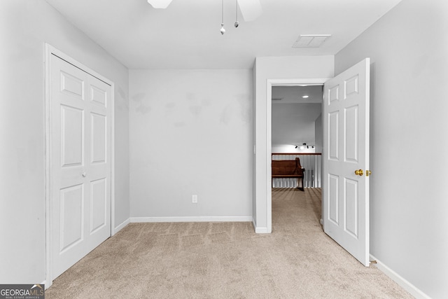 unfurnished bedroom featuring baseboards, a ceiling fan, visible vents, and light colored carpet