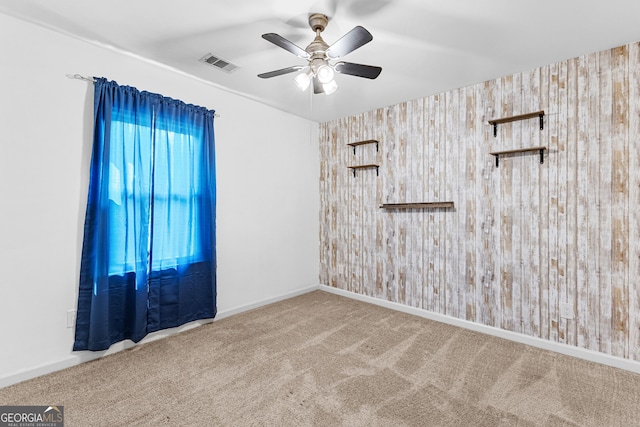 carpeted spare room with baseboards, visible vents, and a ceiling fan