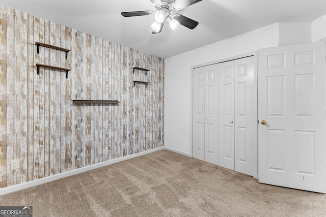 unfurnished bedroom with wallpapered walls, baseboards, a ceiling fan, carpet floors, and a closet