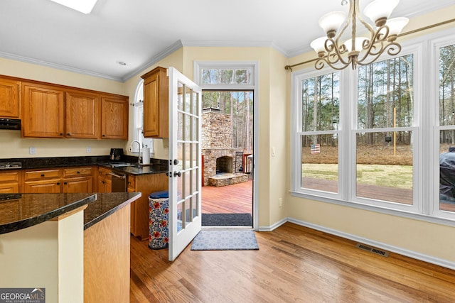 kitchen with light wood-style flooring, a sink, visible vents, ornamental molding, and an inviting chandelier