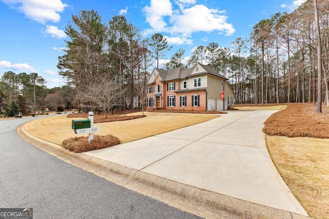 view of front of house featuring concrete driveway, brick siding, and a front lawn