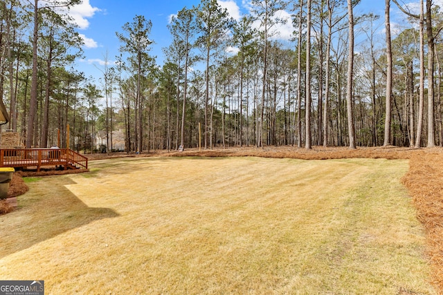 view of yard with a deck and a view of trees