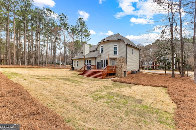 back of house with a chimney, a deck, and a lawn