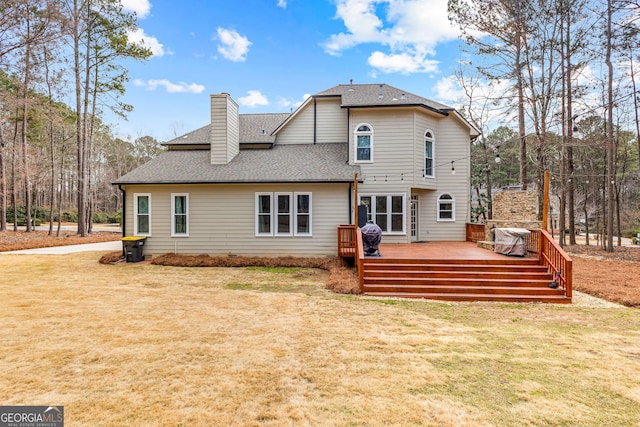 back of house with a shingled roof, a yard, a chimney, and a wooden deck