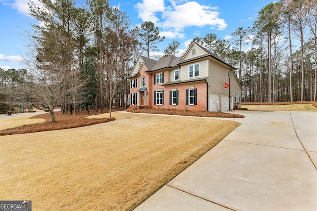 view of front of house featuring a front yard, concrete driveway, brick siding, and an attached garage