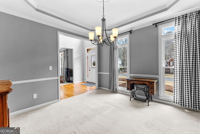 carpeted dining area with baseboards, a tray ceiling, a chandelier, and ornamental molding