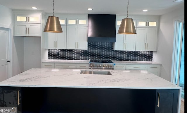 kitchen featuring a kitchen island with sink, premium range hood, high end range, and decorative backsplash