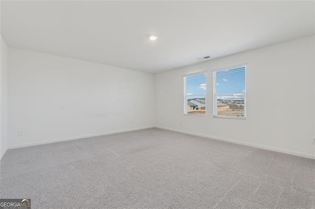 unfurnished room with light colored carpet, visible vents, and baseboards