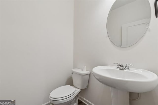 half bath with baseboards and toilet